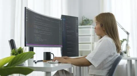 Focused female programmer typing code on computer while working on new proj.. Stock Photos