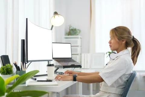 Focused female software developer working with program code on wide display.. 写真素材