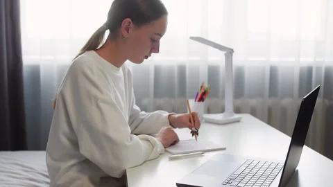 Focused female student doing homework using laptop at home Stock Footage 292729481