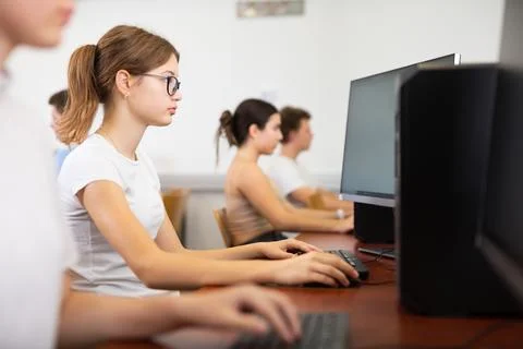 Focused female student in glasses using PC and studying computer science in the Stock Photos