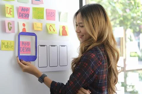 Focused female web developer is planning application for smart phone on white Stock Photos
