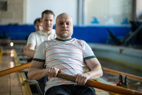 Focused forced rowing athletes train intensely on rowing simulator during Stock-Fotos