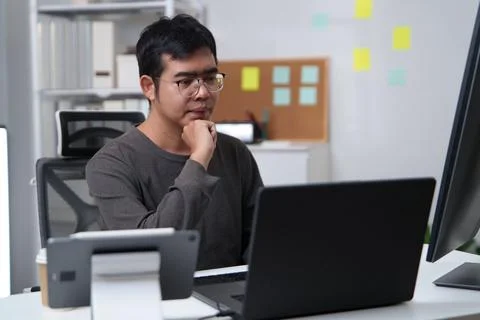 Focused freelance programmer developer working on a laptop in an office setti Stock Photos
