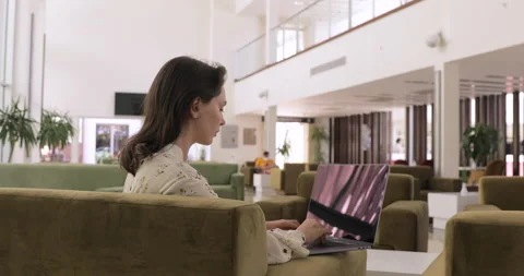 Focused freelancer working on laptop computer while sitting on hotel lobby bar.  Stock Footage 154336063