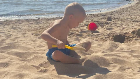 Focused Fun: Little Boy Builds Sandcastles on a Serene Sunny Beach Video stock 318938320