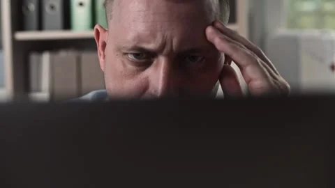 Focused gaze of a middle-aged man working in an office behind a laptop screen Stock Footage 307597716