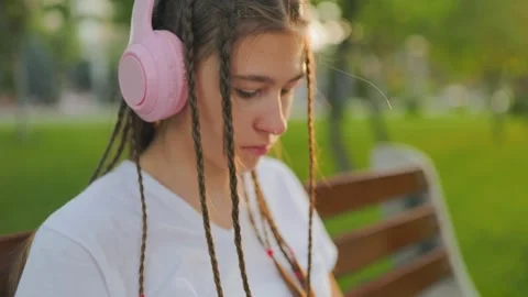 Focused Generation Z adolescent reading on tablet with pink headphones. Zoomer Video stock 340924796