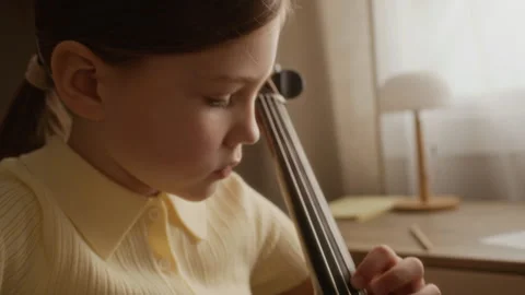 Focused Girl Practicing Cello during Classical Music Lesson at Home Stock Footage 336176610