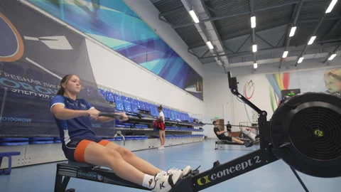 Focused girl repeats pulling exercise on rowing machine Stock Footage 316752029