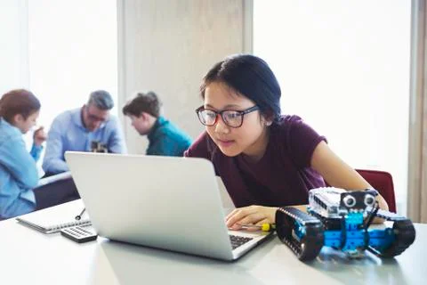 Focused girl student programming robotics at laptop in classroom Foto stock
