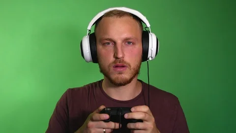 Focused guy in headphones playing a console. Red face, sweat flowing in a stream Video stock 115508418