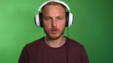 Focused guy in headphones playing console. Red face, sweat flowing by stream Video stock 115508487