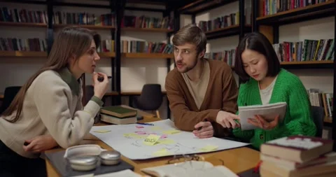 Focused guy student communicates with his female colleagues while sitting at a Stock Footage 313357554