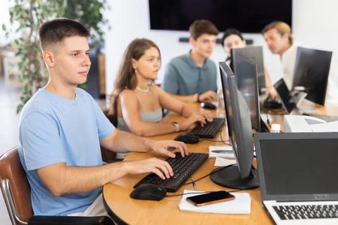 Focused guy studying in computer lab with fellow students Fotos de archivo