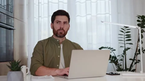 Focused guy using modern laptop and thoughtfully looking aside at home Stock-Footage 262022166