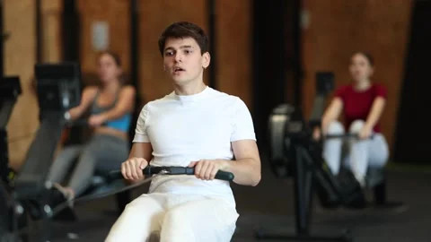 Focused guy works out with rowing machine during class at fitness club Stock Footage 315031702