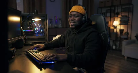 A focused guy in a yellow cap with a headset is playing a video shooter Stock Footage 178591960