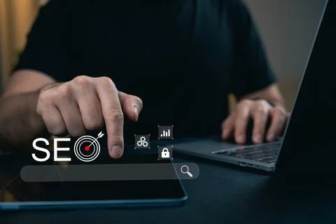 Focused hand interacting with SEO target icons and sleek laptop for digital.. Stock Photos