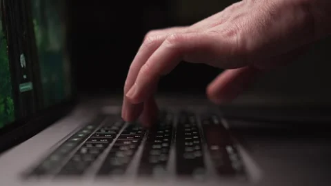 Focused hands expertly typing on a laptop keyboard illuminated by dim ambient Stock Footage 305280326