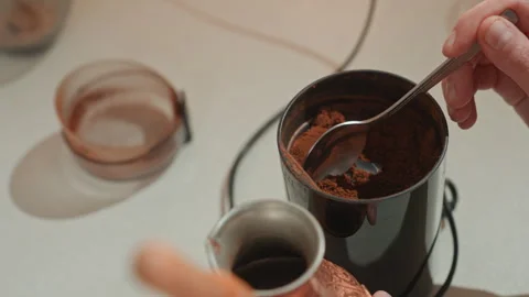 Focused hands transfer coffee grounds into copper coffee pot for brewing Stock Footage 337312929