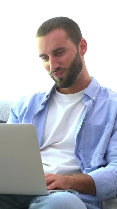 Focused handsome bearded man freelancing from home, sitting on a sofa Stock Footage 345079431