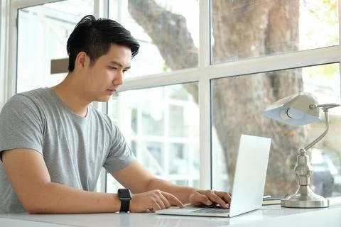 Focused handsome businessman working with computer at bright office. Stock Photos