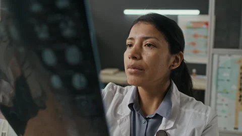 Focused Hispanic Female Doctor Analyzing Brain Mri Scan in Hospital Stock Footage 339785731