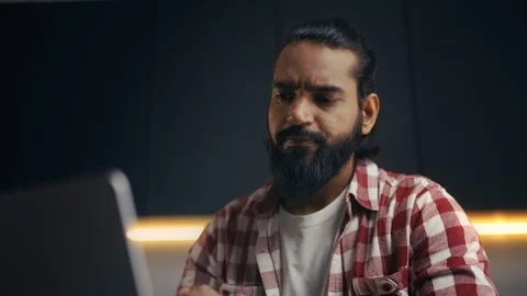 Focused Indian male programmer working on laptop and drinking coffee at home Stock Footage 313281305