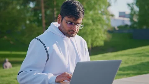 Focused indian programmer working on laptop in park Stock Footage 310251288