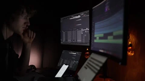 A focused individual analyzes data on multiple monitors displaying financial cha Stock Footage 297112319