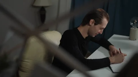 A Focused Individual Engaged in Writing at Their Desk in a Modern and Stylish Stock Footage 316061889