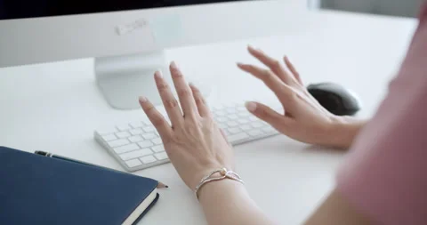 A focused individual engages with their computer in a minimalist home office Stock Footage 297447375
