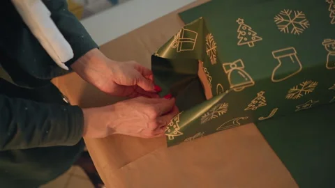 Focused individual meticulously preparing holiday gift wrapping details. Woman Stock Footage 345168314