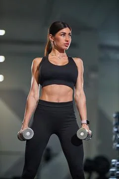 Focused individual performs strength training exercises holding dumbbells in Stock Photos