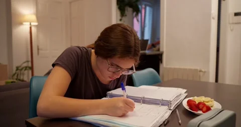 A focused individual sits at a table, engrossed in studying. Stock Footage 334776384