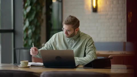 Focused Individual Working Creatively at a Cozy Cafe, Engaged in Writing and Stock Footage 344799862