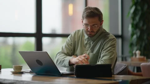 Focused Individual Working on Laptop in Modern Cafe Setting, Utilizing Stock Footage 344799915