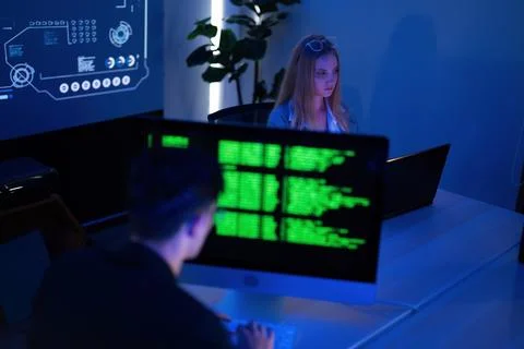 Focused individuals working on computer programming in a dark tech workspac.. Foto stock