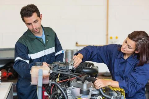 Focused instructor and trainee checking a machine Stock Photos