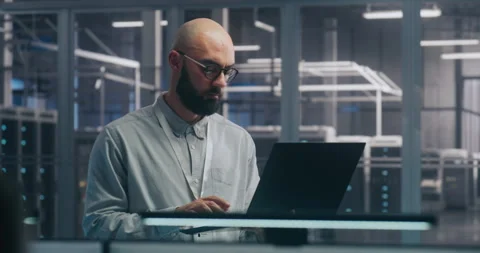 Focused IT Engineer Using Laptop in Server Hall Video stock 325423499