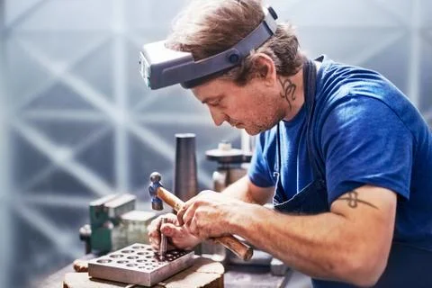 Focused jeweler using hammer in workshop Stock Photos