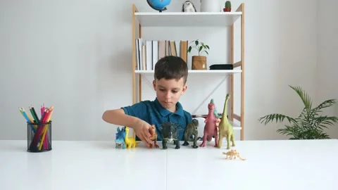 Focused kid playing with dinosaurs at home. Boy learning paleontology Stock Footage 150276311