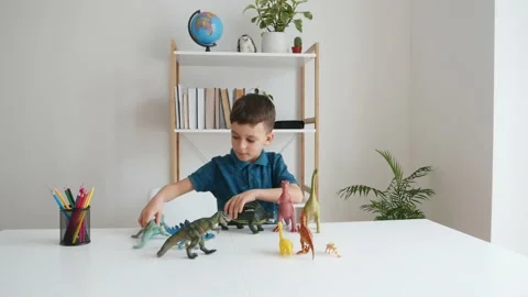 Focused kid playing with dinosaurs at home Stock Footage 150748515