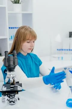 A focused lab technician in a blue uniform and gloves prepares scientific s.. Stock Photos