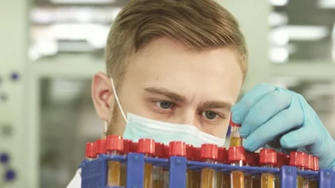 Focused lab technician meticulously examines test tubes filled with assays Stock Footage 311990834