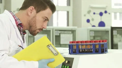 Focused laboratory assistant meticulously analyzes test tubes while documenting Stock Footage 311945898