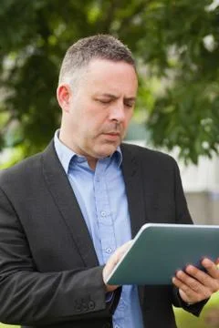 Focused lecturer using his tablet outside on campus Фото