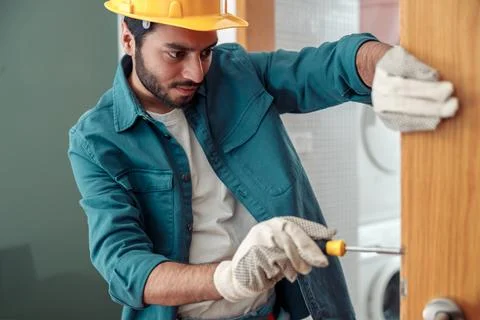 Focused Locksmith workman in uniform installing door knob. Professional repair Foto stock