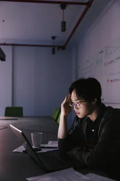 Focused male computer programmer working late at laptop in office 스톡 사진