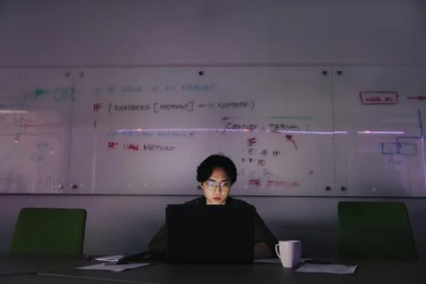 Focused male computer programmer working late at laptop in office 스톡 사진